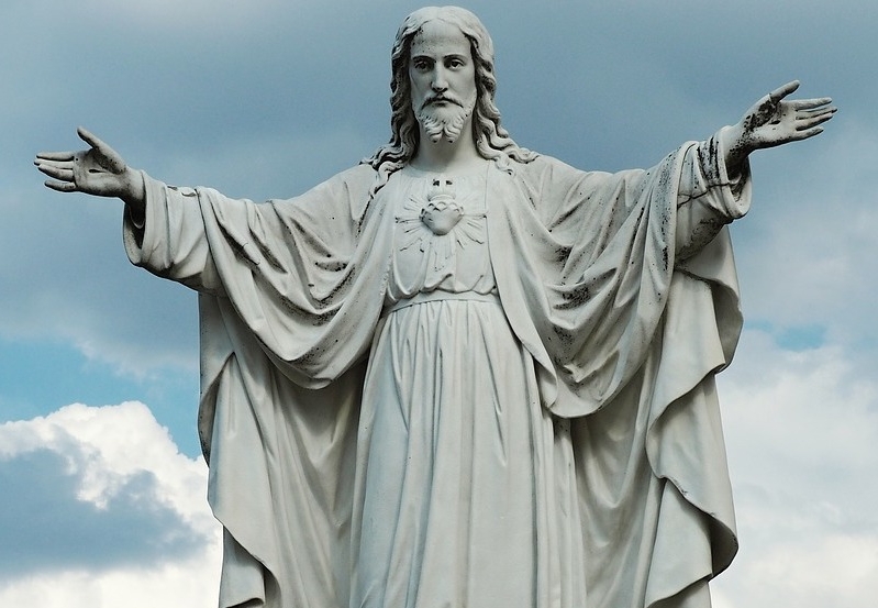 Herz-Jesu-Statue aus hellem Stein: Jesus Christus breitet die Arme aus.